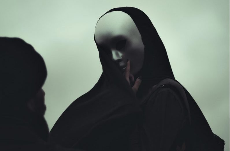 Photo by Marcelo Chagas Black and white of anonymous man and anonymous person in white mask touching covered face