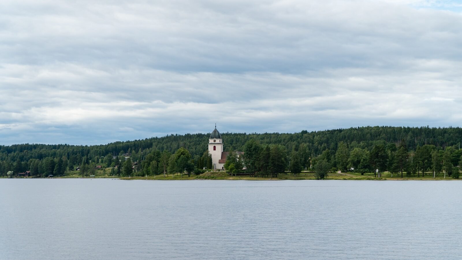 Ledare 3 a body of water with trees and a building in the background